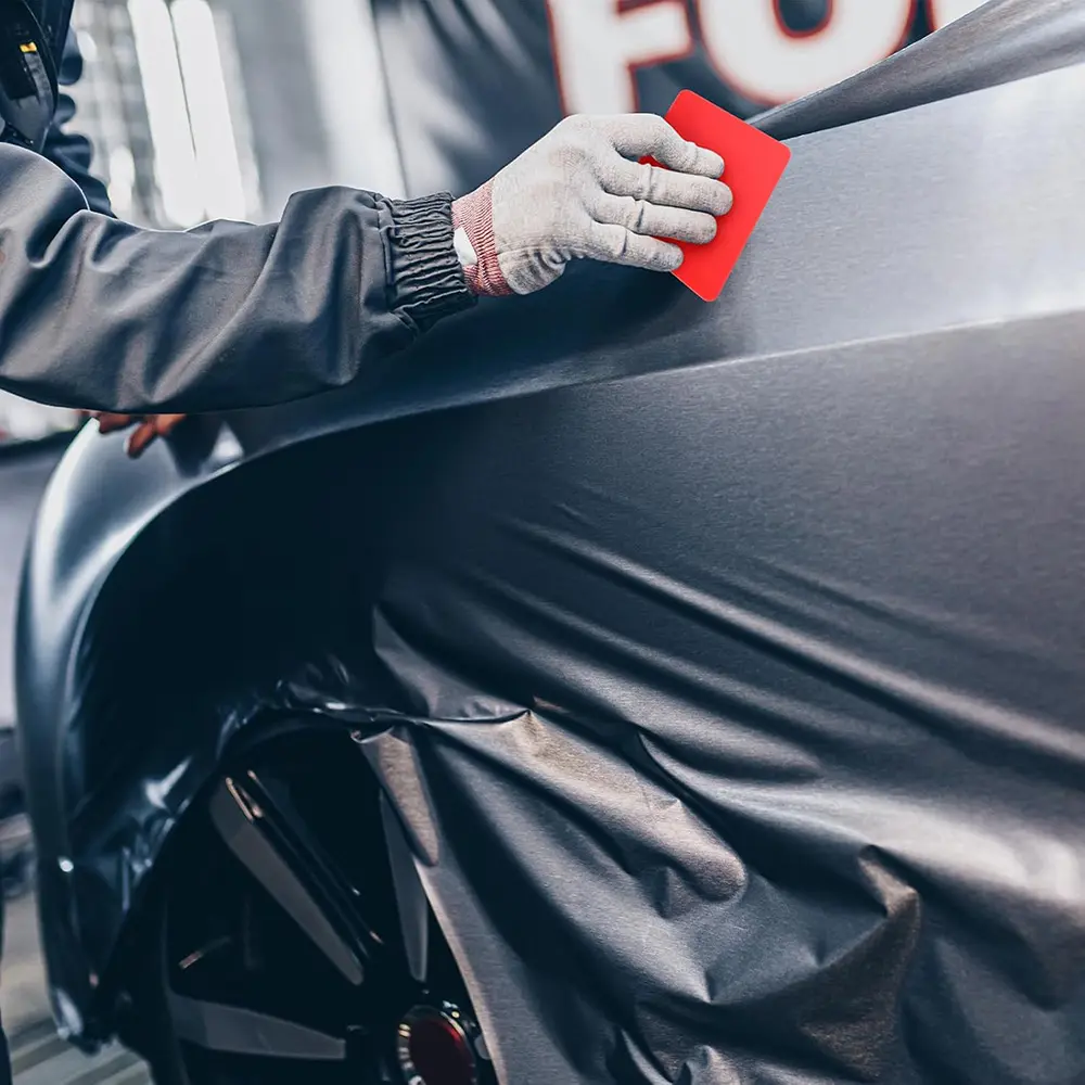 Using squeegee to smooth car window tint film